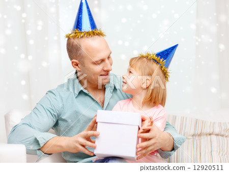 father and daughter in party caps with gift box 12920511