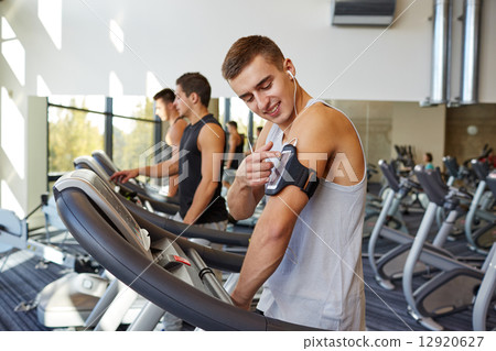 man with smartphone exercising on treadmill in gym man with smartphone exercising on treadmill in gym 12920627