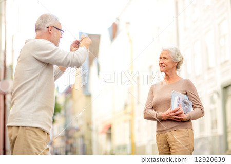 senior couple photographing on city street 12920639