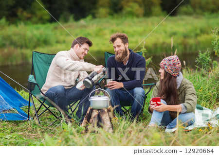 group of smiling tourists cooking food in camping 12920664