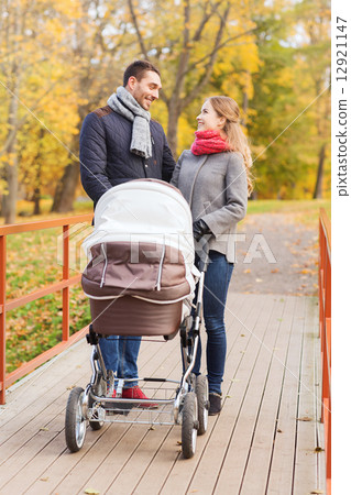 smiling couple with baby pram in autumn park smiling couple with baby pram in autumn park 12921147