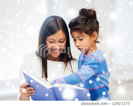 mother and daughter with book indoors 12921177