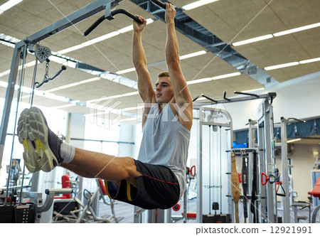 man flexing abdominal muscles on pull-up bar 12921991