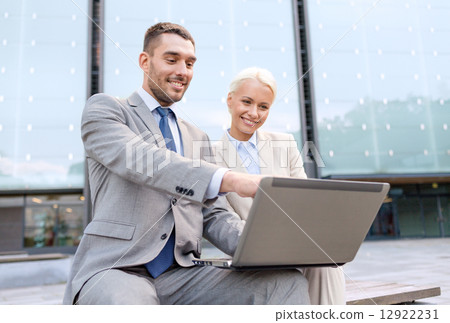 smiling businesspeople with laptop outdoors smiling businesspeople with laptop outdoors 12922231