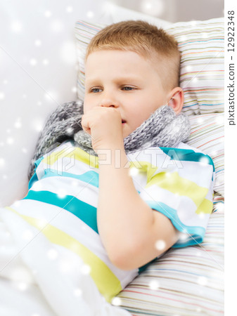 ill boy with scarf lying in bed and coughing ill boy with scarf lying in bed and coughing 12922348