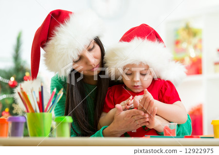 child and mom in Santa hats making christmas tree of plasticine child and mom in Santa hats making christmas tree of plasticine 12922975