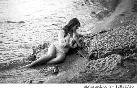 Monochrome photo of sexy lonely woman lying on rocky beach 12931730