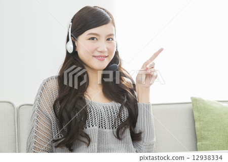 A woman wearing a headset and operating a personal computer 12938334
