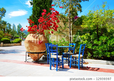 The amphora with flowers and traditional Greek table and chairs 12939397
