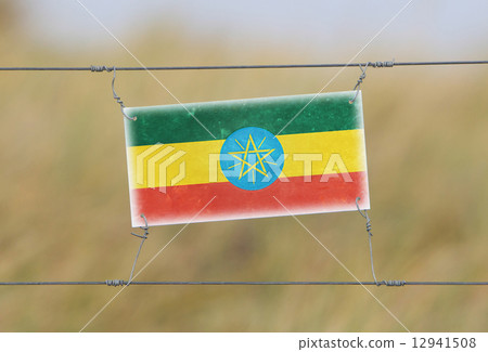 Border fence - Old plastic sign with a flag Border fence - Old plastic sign with a flag 12941508