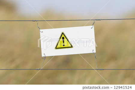 Border fence - Old plastic sign with a flag Border fence - Old plastic sign with a flag 12941524