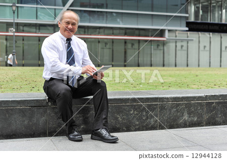 Portrait of an senior businessman using tablet in an urban setting 12944128