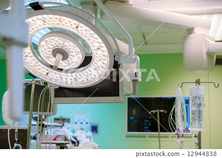 Surgical lamp in operation surgery room. Surgery monitors and IV solutions are on background. Green  12944838