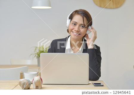 Asian Businesswoma at Cafe using Headphone , Laptop . Asian Businesswoma at Cafe using Headphone , Laptop . 12945641