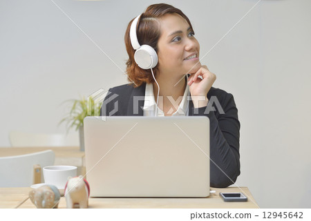 Asian Businesswoma at Cafe using Headphone , Laptop . Asian Businesswoma at Cafe using Headphone , Laptop . 12945642