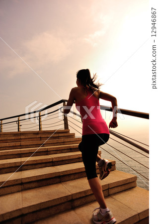 healthy lifestyle sports woman running on stone stairs seaside  12946867