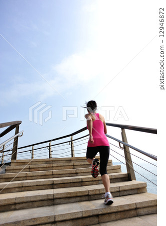 healthy lifestyle sports woman running on stone stairs seaside  12946872