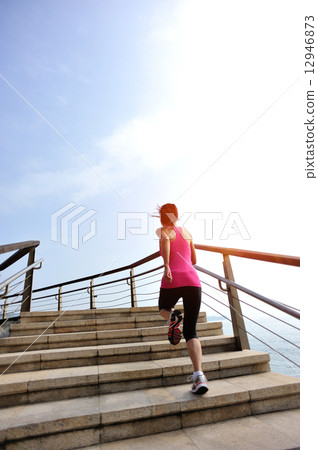healthy lifestyle sports woman running on stone stairs seaside  12946873
