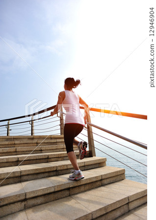 healthy lifestyle sports woman running on stone stairs seaside  12946904
