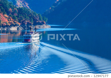 Uonuma City, Niigata Prefecture · Okadadenko Lake with autumn leaves and a pleasure boat 12947177