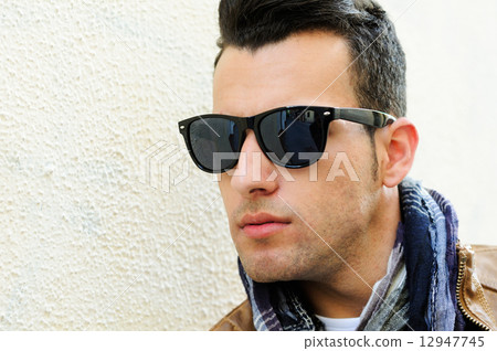 Attractive man wearing tinted sunglasses in urban background Attractive man wearing tinted sunglasses in urban background 12947745