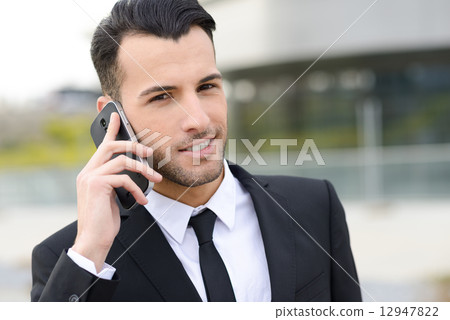Attractive young businessman on the phone in an office building Attractive young businessman on the phone in an office building 12947822