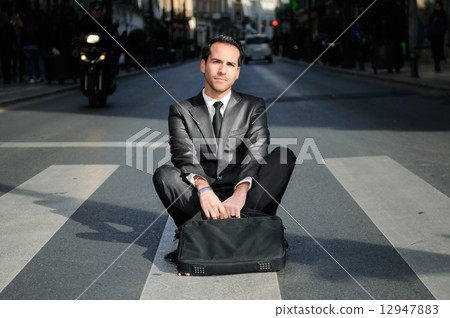 Young handsome businessman sitting in a crosswalk Young handsome businessman sitting in a crosswalk 12947883