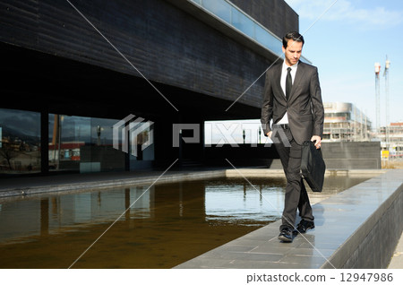 Portrait of a handsome young business man walking in the street Portrait of a handsome young business man walking in the street 12947986