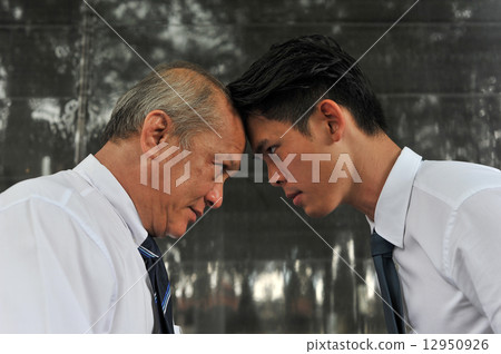 Profile of two Asia white collar men facing off each other with the foreheads locking together Profile of two Asia white collar men facing off each other with the foreheads locking together 12950926