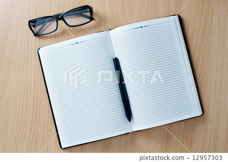 Open diary with a pen and glasses Open diary with a pen and glasses 12957303