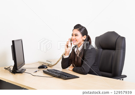 Smiling corporate business women on the phone at her office Smiling corporate business women on the phone at her office 12957939