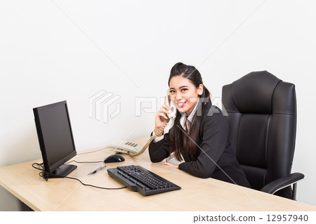 Smiling corporate business women on the phone at her office Smiling corporate business women on the phone at her office 12957940