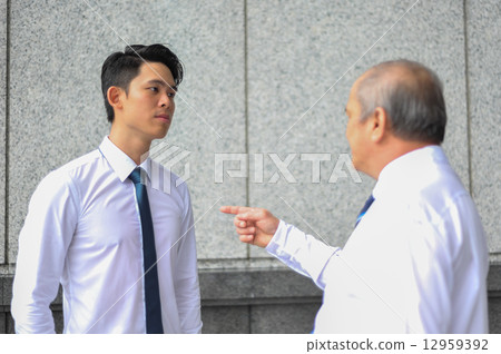Two Asian men in shirt and tie in dispute with the older man pointing finger at the younger man 12959392