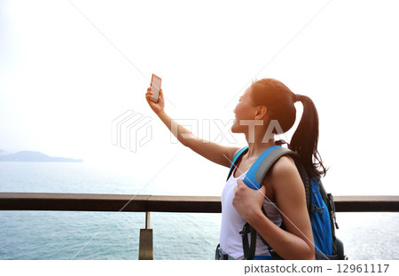 woman hiker taking self photo on sunrise seaside  12961117