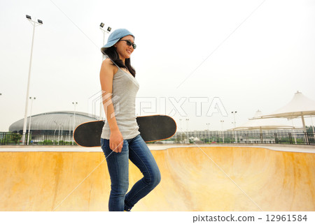 young woman skateboarder walking at skatepark young woman skateboarder walking at skatepark 12961584