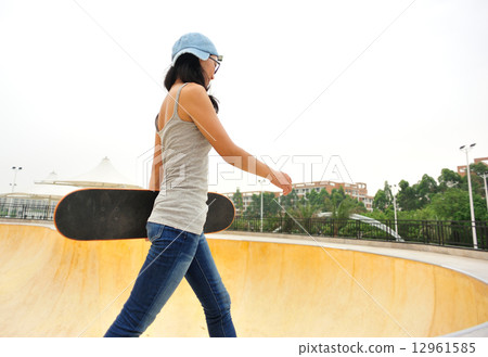 young woman skateboarder walking at skatepark 12961585