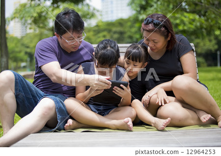 Young Asian family bonding in park playing tablet 12964253