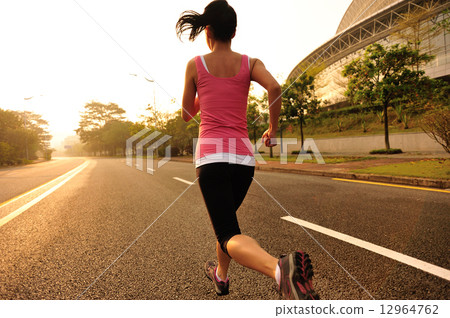 young fitness woman running at sunrise road 12964762