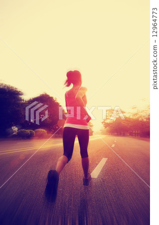young fitness woman running at sunrise road 12964773