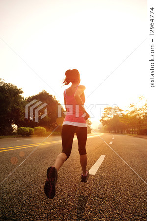 young fitness woman running at sunrise road 12964774