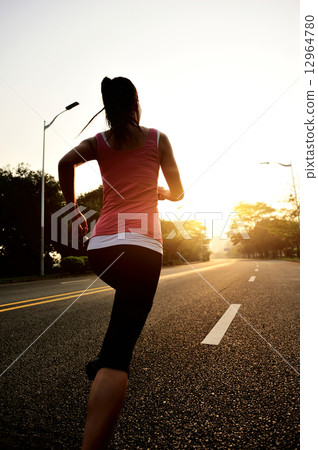 young fitness woman running at sunrise road 12964780