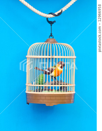 Birdcage with artificial colorful bird isolated on blue. 12966958