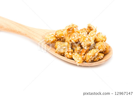 Crispy sugared nuts with wooden spoon isolated on white. 12967147