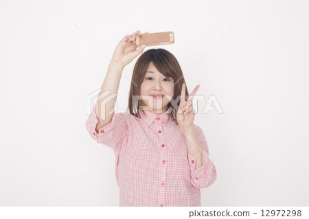 拍與她的手機的婦女一張照片 12972298