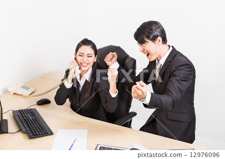 Two business person celebrate their success at the office with fist clench 12976096