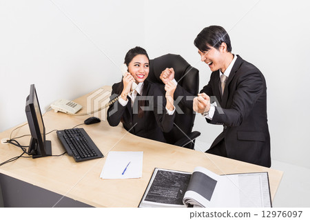 Two business person celebrate their success at the office 12976097