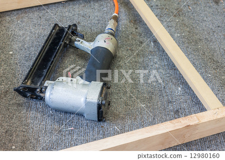 Old air nailer on table with wooden frame 12980160