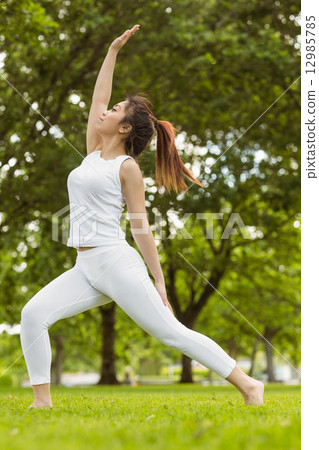 Toned woman doing stretching exercises in park Toned woman doing stretching exercises in park 12985785
