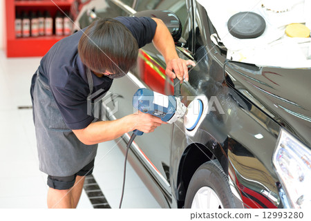 The man is polishing the car. 12993280