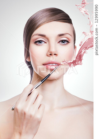 woman with brush on lips and paint splash 12995990